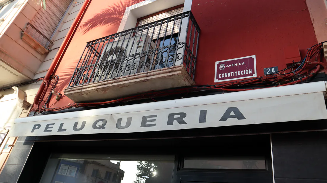 La placa de la Avenida Constitución y el número 24 sobre el rótulo PELUQUERÍA.